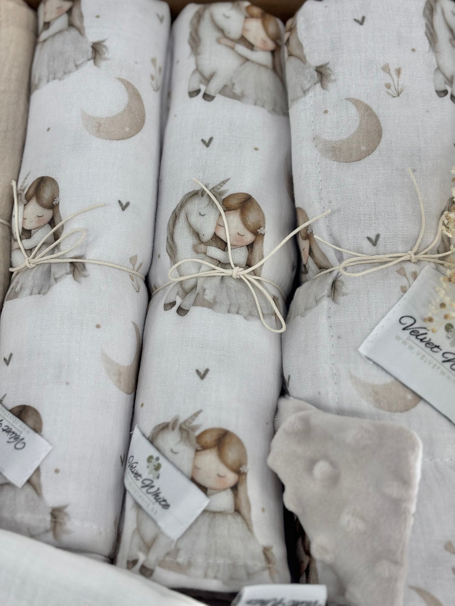 Folded fabric with a pattern of children and rabbits, tied with twine, on a white background.