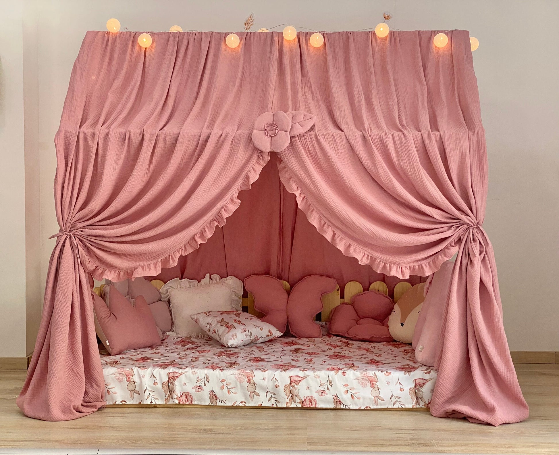 Dusty rose canopy with ruffles over Montessori floor bed