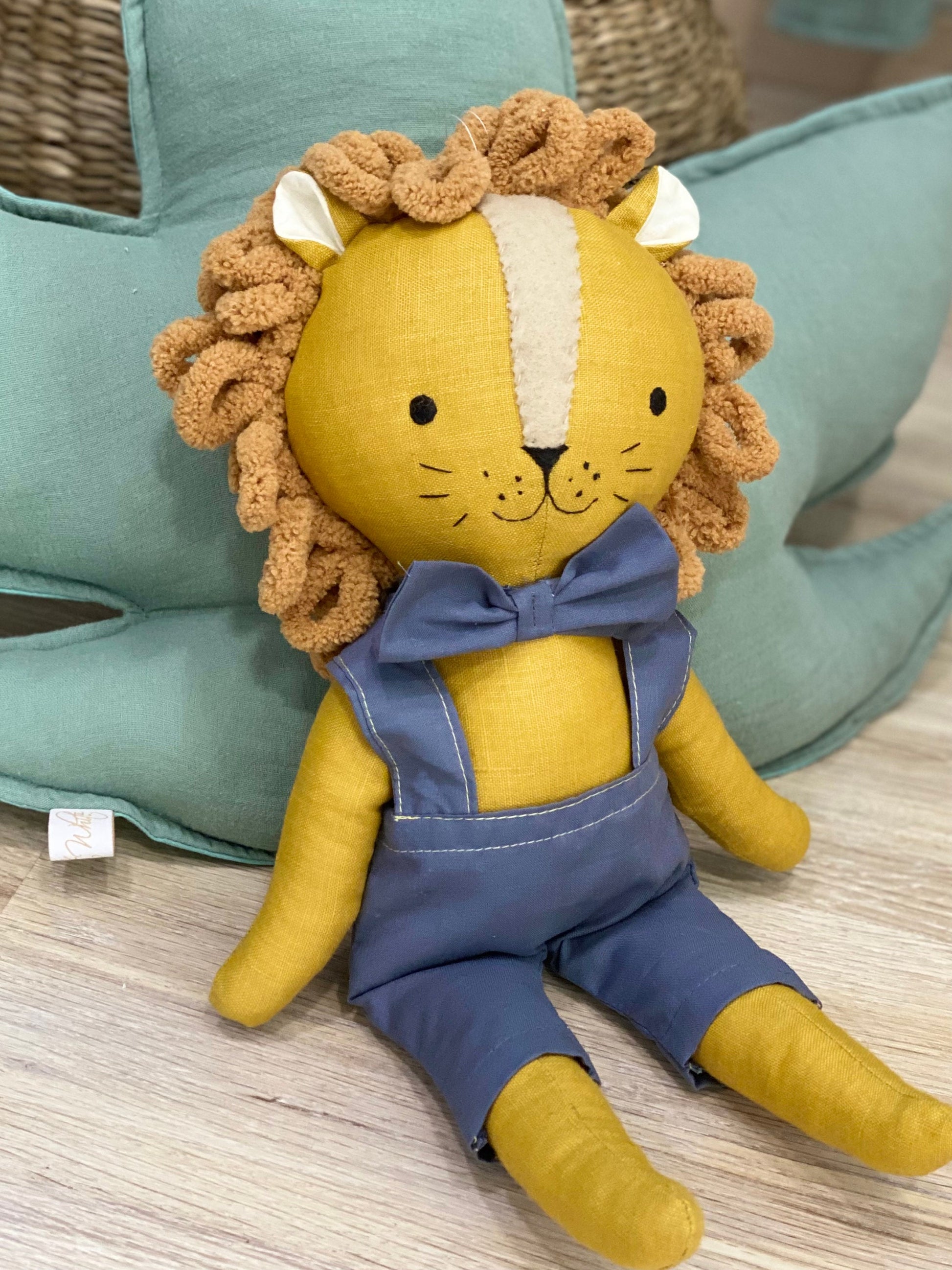 Handmade safari lion fabric doll sitting on wooden floor in neutral kids room