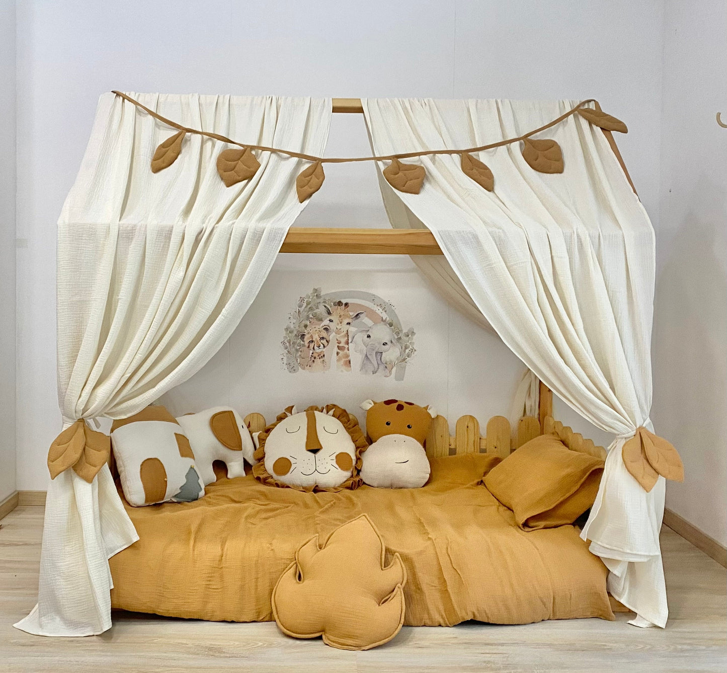 Cream canopy with leaf tiebacks over Montessori bed