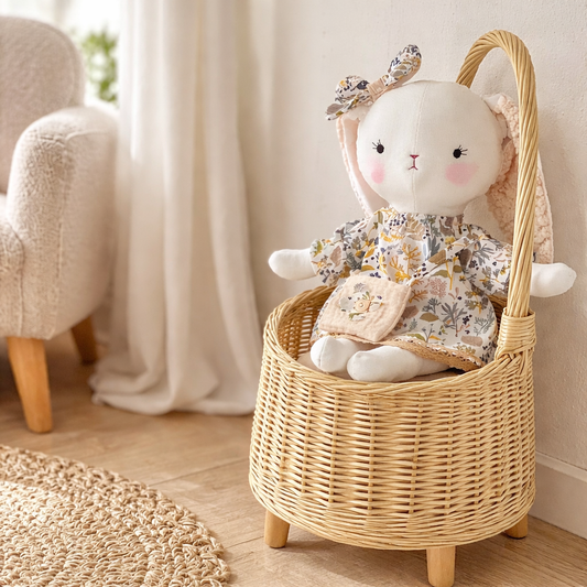 Handmade bunny fabric doll sitting on wooden floor in neutral kids room